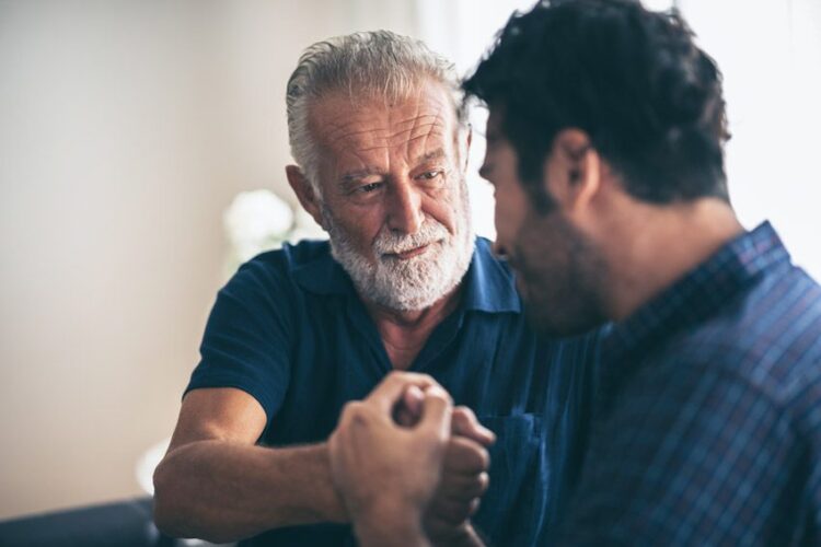 senior man and his son bonding - talking sitting close on couch - make a plan