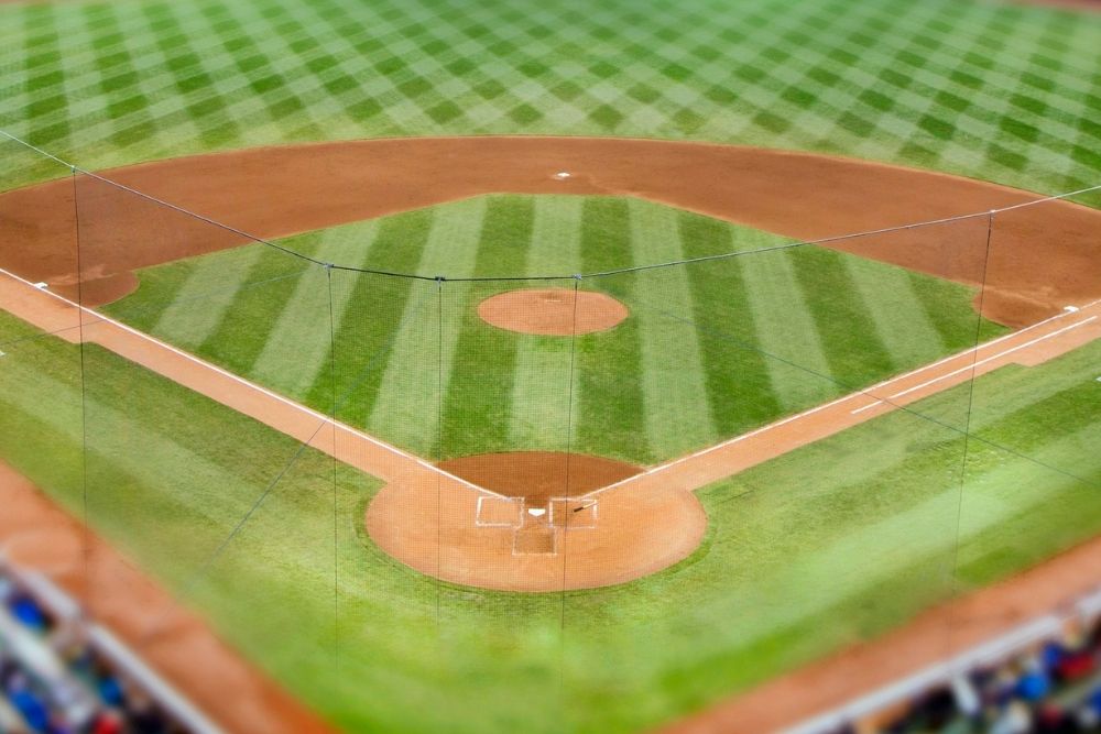 An overhead view of a baseball field, showing the infield, home plate, and neatly mowed grass patterns.
