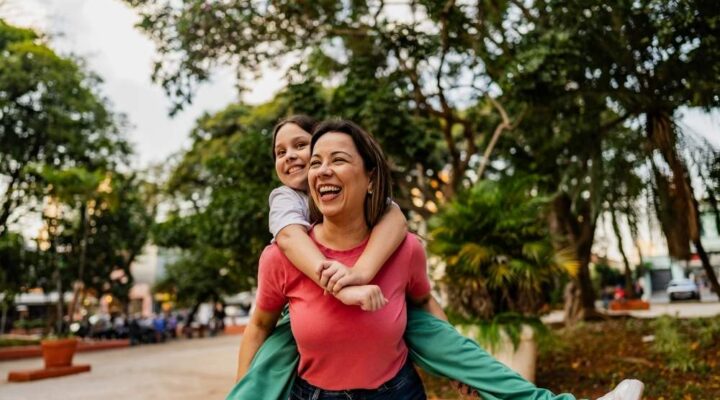 Bel Aire - Walk Your Way to Recovery Benefits. A woman and her daughter walk down a street. The moth is carrying the girl on her back as both smile.